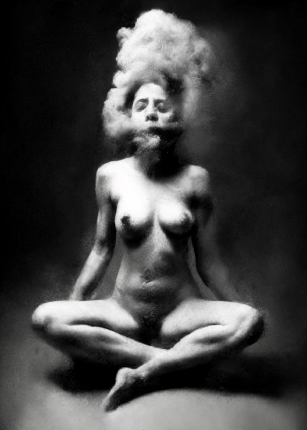 Black and white fine art photograph of a nude female figure sitting cross-legged with her hair styled in a voluminous updo, set against a dark studio background. Unmoored series.