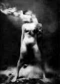A black and white fine art photograph of a nude female figure standing on a dark, smoky background with light rays hitting her body.  Unmoored series.