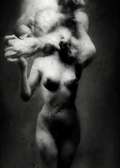 Black and white fine art photograph of a nude female figure with a smoky, ethereal overlay, set against a dark textured studio background. Unmoored series.
